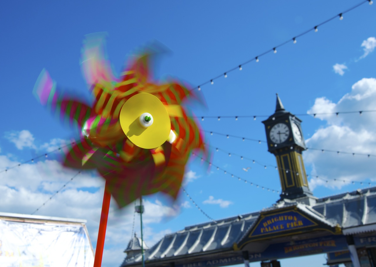 Seaside windmill with Brighton Palace Pier in the background photographed by Beowulf Mayfield